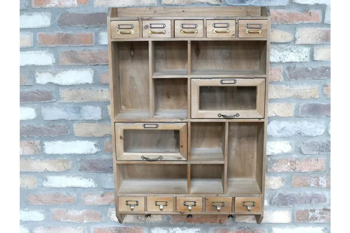 Wooden wall shelf unit with small drawers and cubby compartments against brick wall