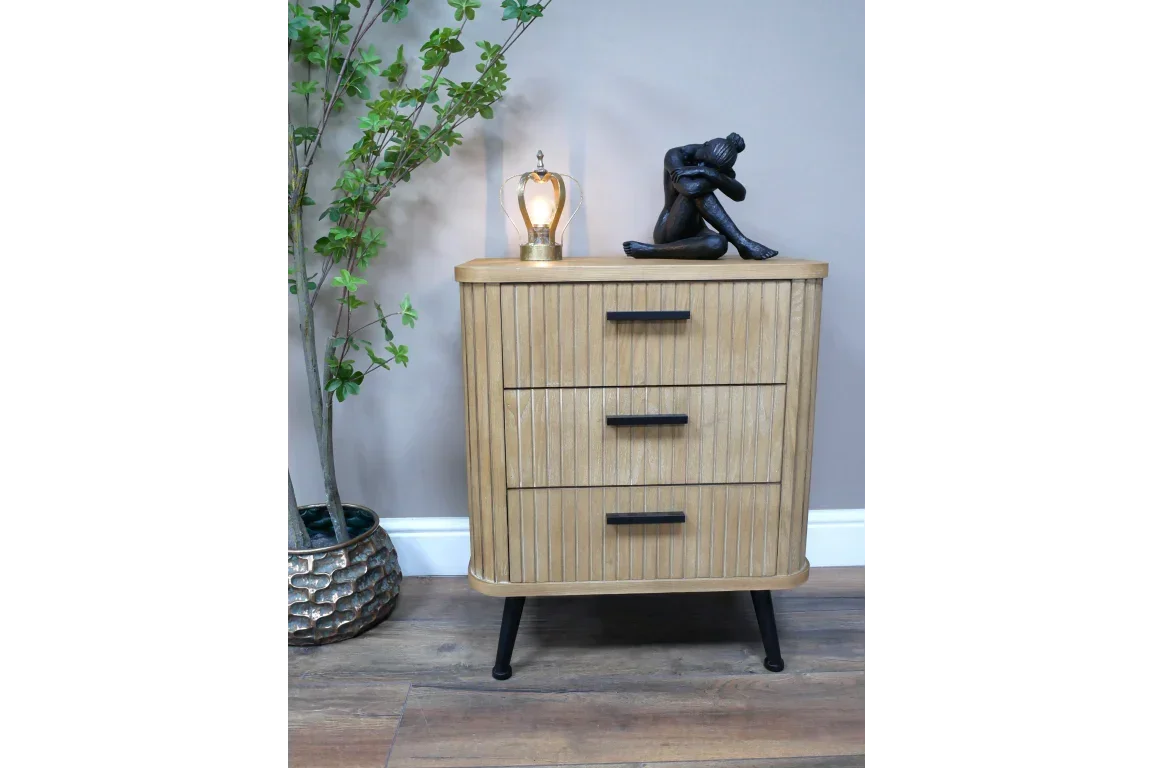 Three drawer oak bedside cabinet with black handles, lamp, and figure ornament on top