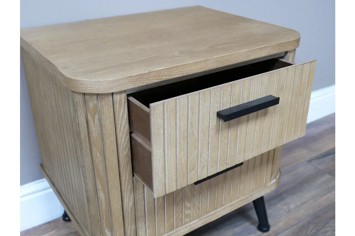 Oak bedside table with grooved wood finish, black handle, and partially open drawer