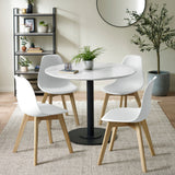 Dining room setting with four white chairs and round white marble table on woven rug