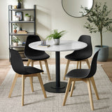 Black chairs with light wooden legs around round white marble table with black base in beige room with plants