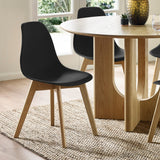 Two black dining chairs with light wood legs on woven rug near oak dining table