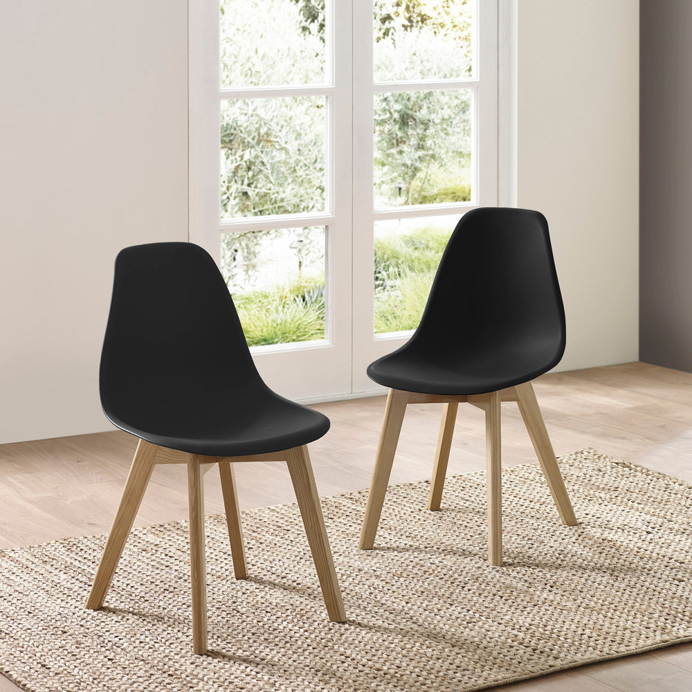 Pair of black dining chairs with light oak legs in room with double doors and wood floor