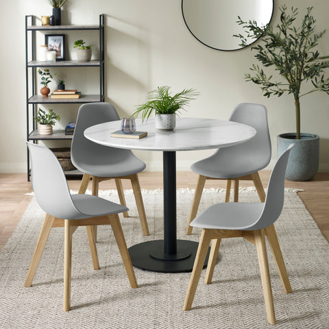 Four grey dining chairs with wooden legs around a round white marble table in a room with neutral decor