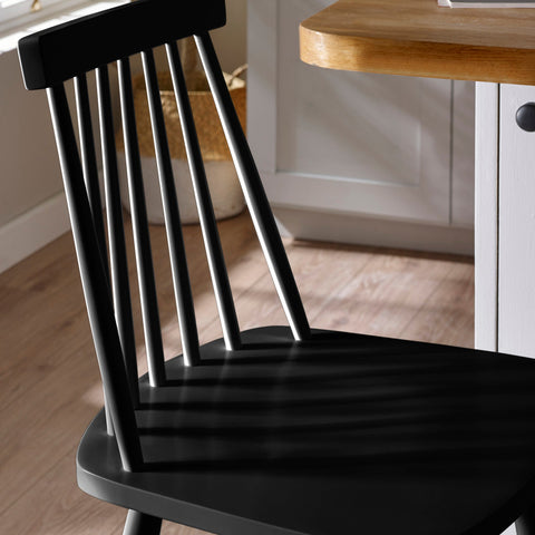 Close-up of black wooden bar stool top corner showing spindle back and seat corner.