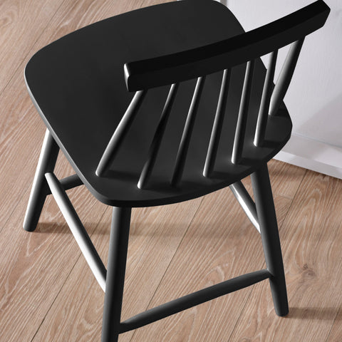 Close-up of black wooden bar stool back showing smooth finish and spindle detail on wood floor.