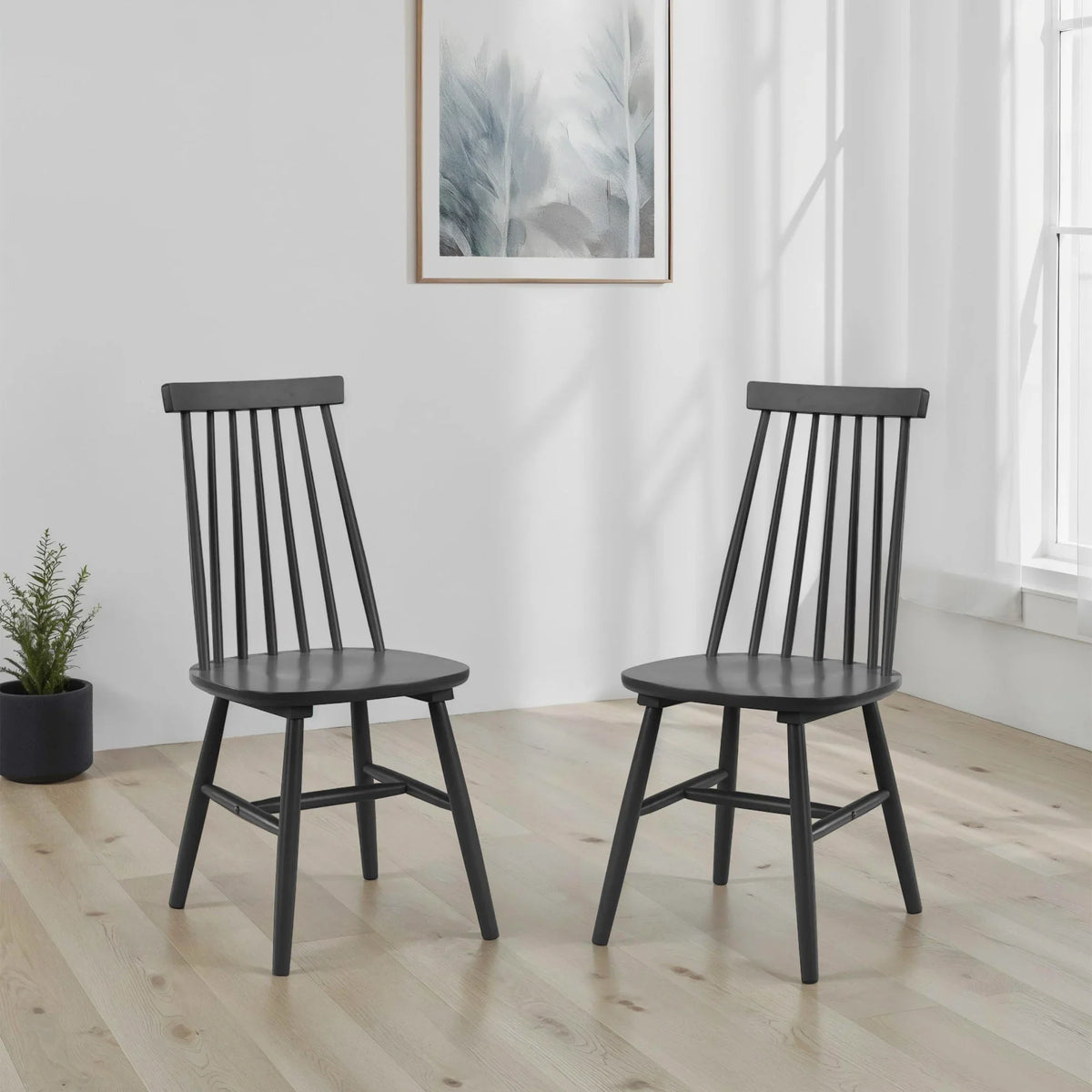 Pair of black wooden dining chairs with spindle backs in bright room