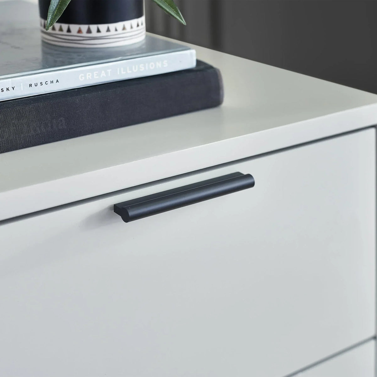 Silk grey bedside table drawer with black handle and books on top