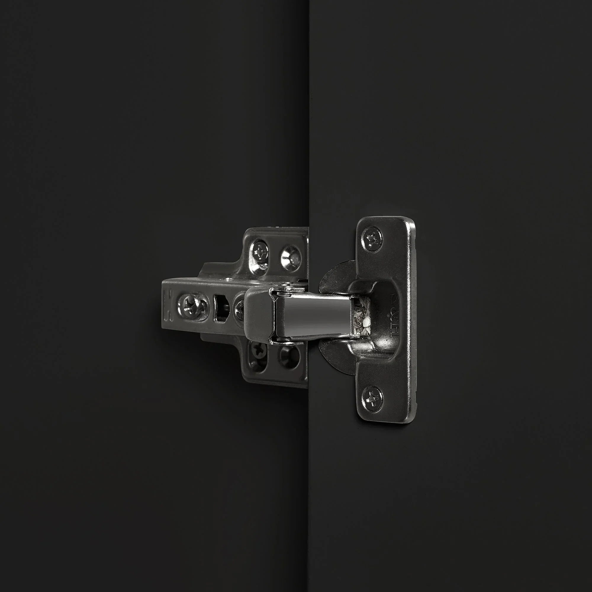 Closeup of metal hinge on black wardrobe door with matte finish