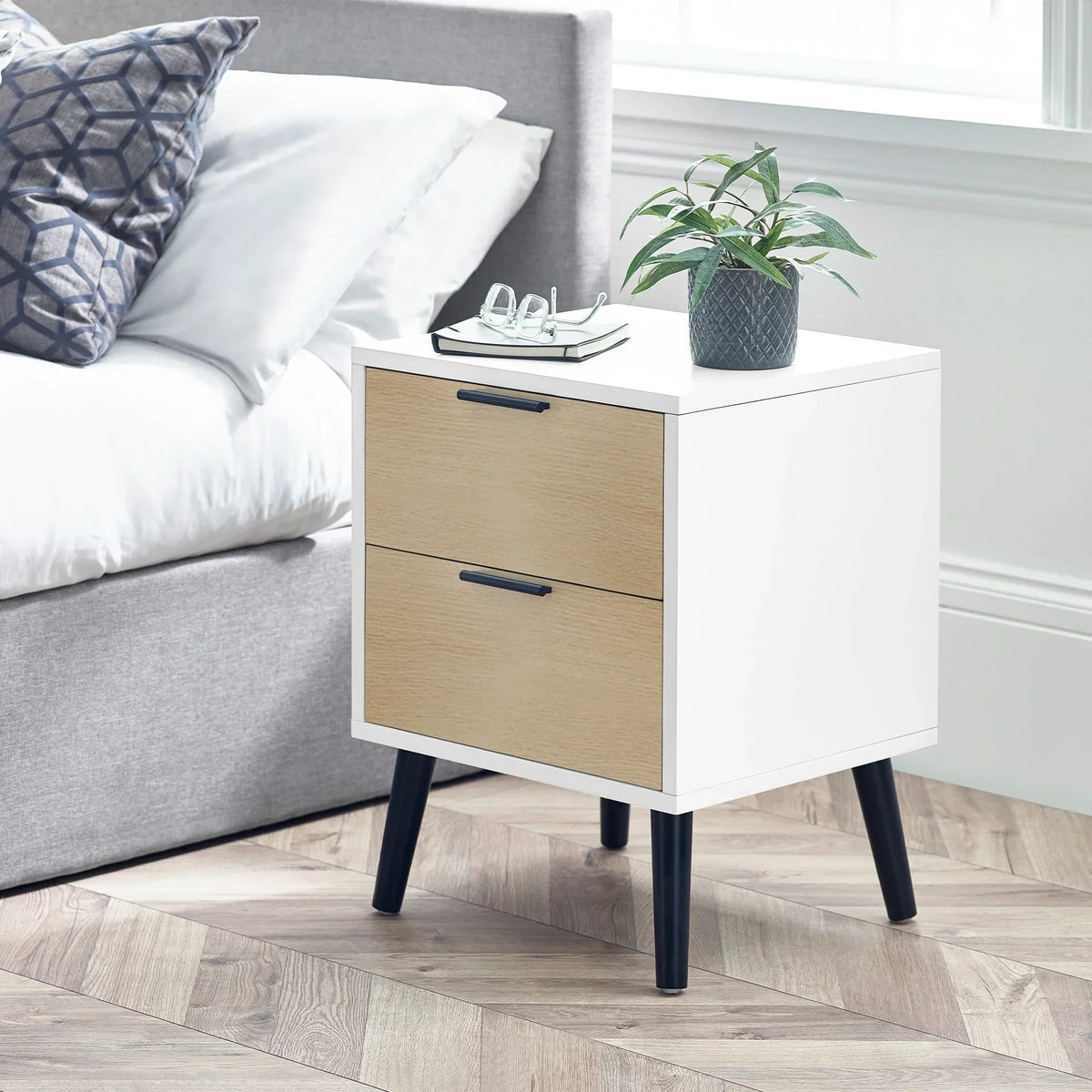 White and oak two drawer bedside table with black legs in modern bedroom setting