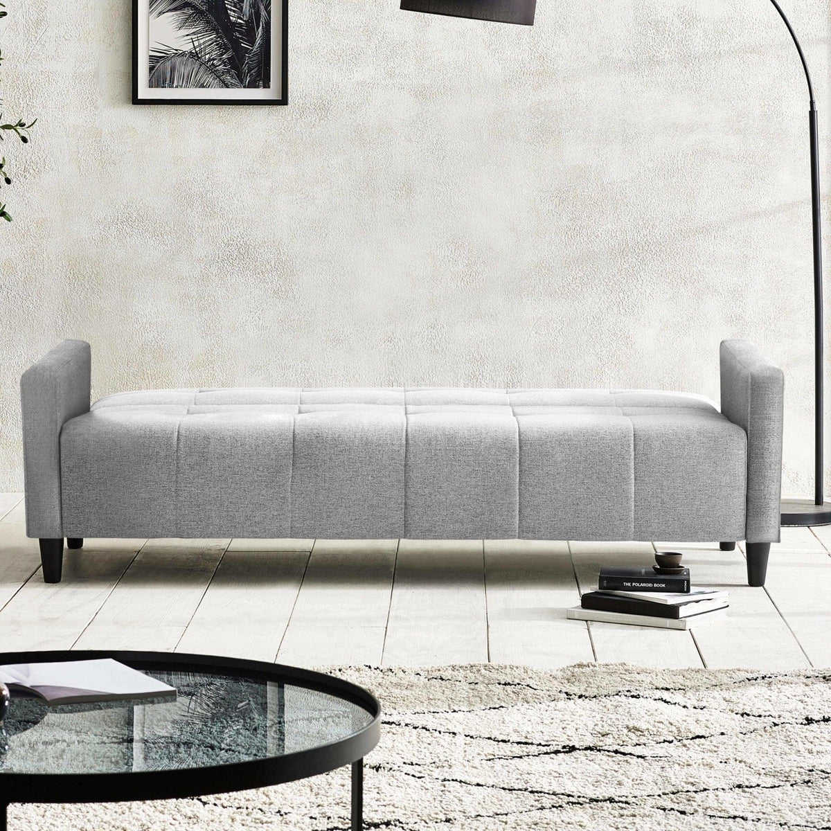 Light grey upholstered bench seat with low arms, set on wooden legs in a modern living room