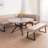 A round dining table with a light gray wood-look top and black metal legs, paired with a beige upholstered bench and matching curved sectional seating in a bright room with wood flooring.