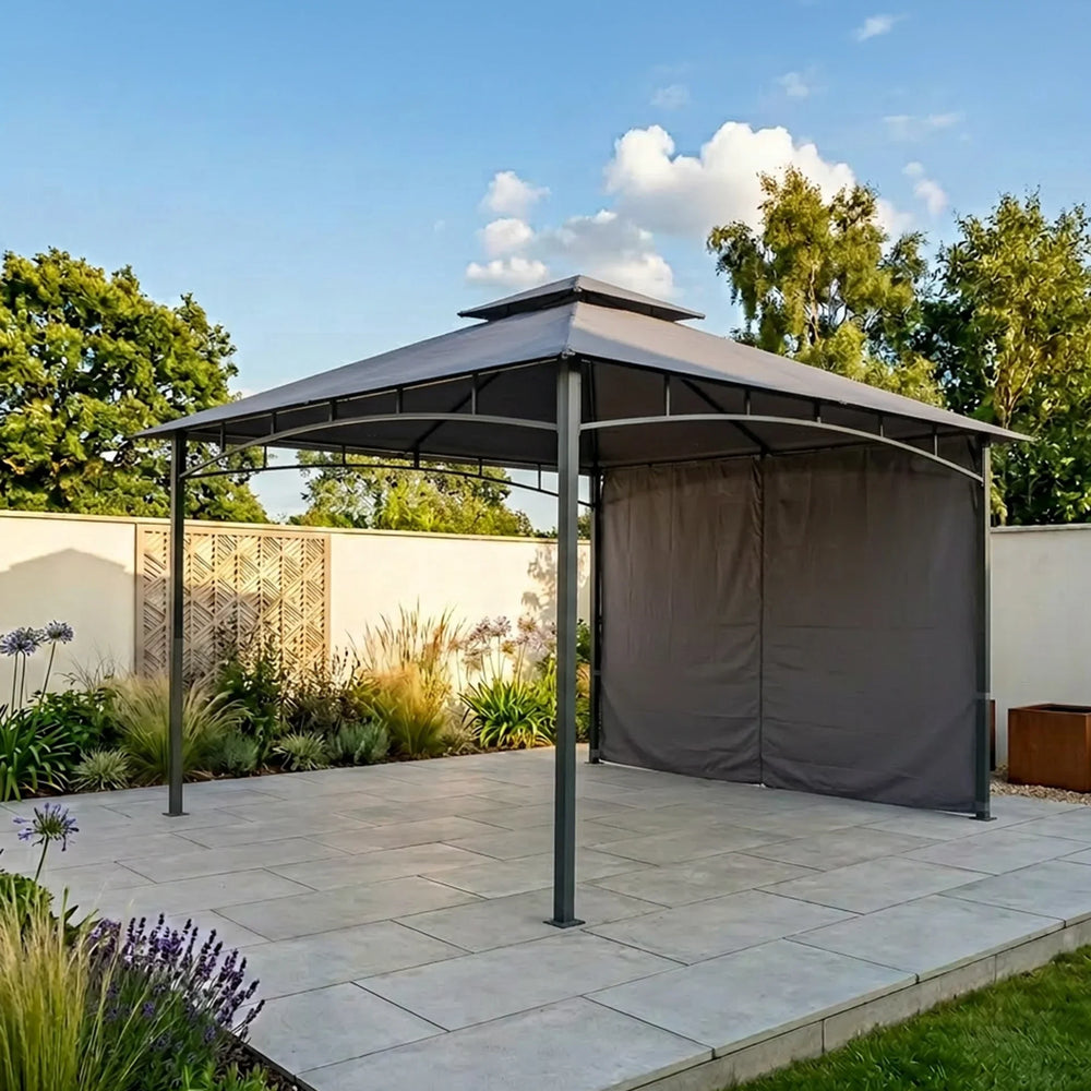 Grey metal garden gazebo with canopy and side panel on paved patio in landscaped yard