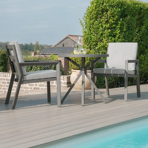 Aluminum patio bistro set with two cushioned chairs and round table beside pool