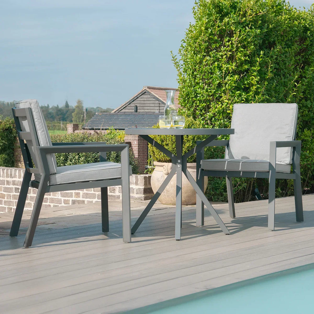 Aluminium garden bistro set with two grey cushioned chairs and round table by a pool