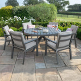 Grey aluminium outdoor dining set with six cushioned chairs on stone patio in garden