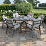 Aluminium outdoor dining set with round table and six grey cushioned chairs on patio
