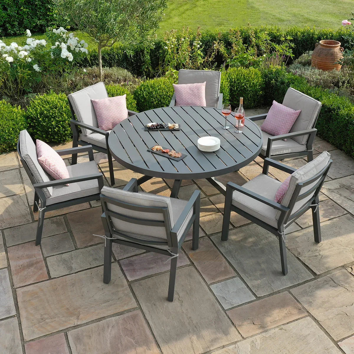 Grey aluminum outdoor dining set with round table and cushioned chairs on patio