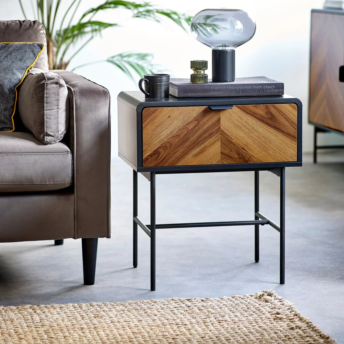 Modern wood and metal bedside table with chevron drawer beside sofa and rug