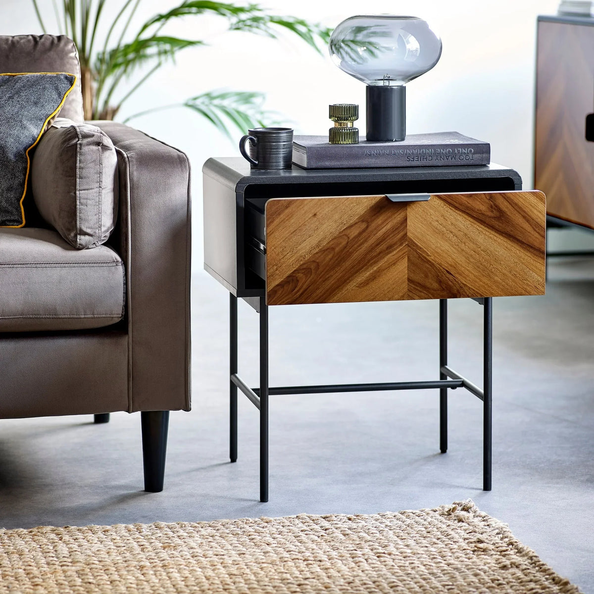 Modern wooden side table with chevron drawer, black metal legs, styled beside sofa