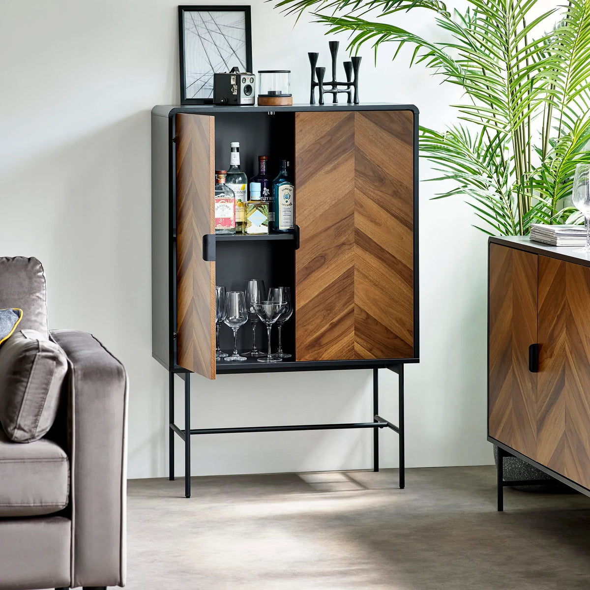 Chevron wood drinks cabinet with black frame, open to display glassware and bottles