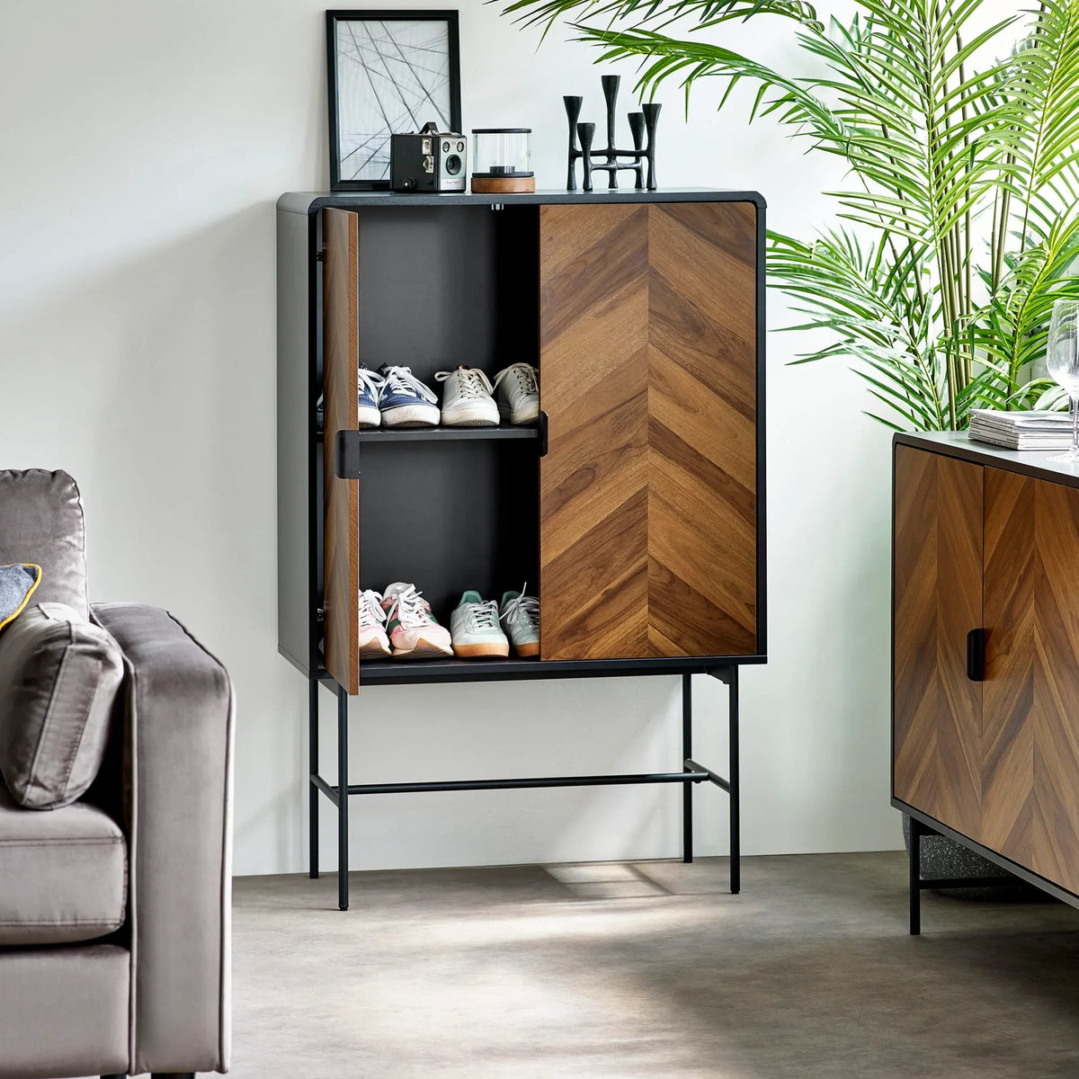 Chevron wood shoe cabinet with black frame, open to show shelves with trainers