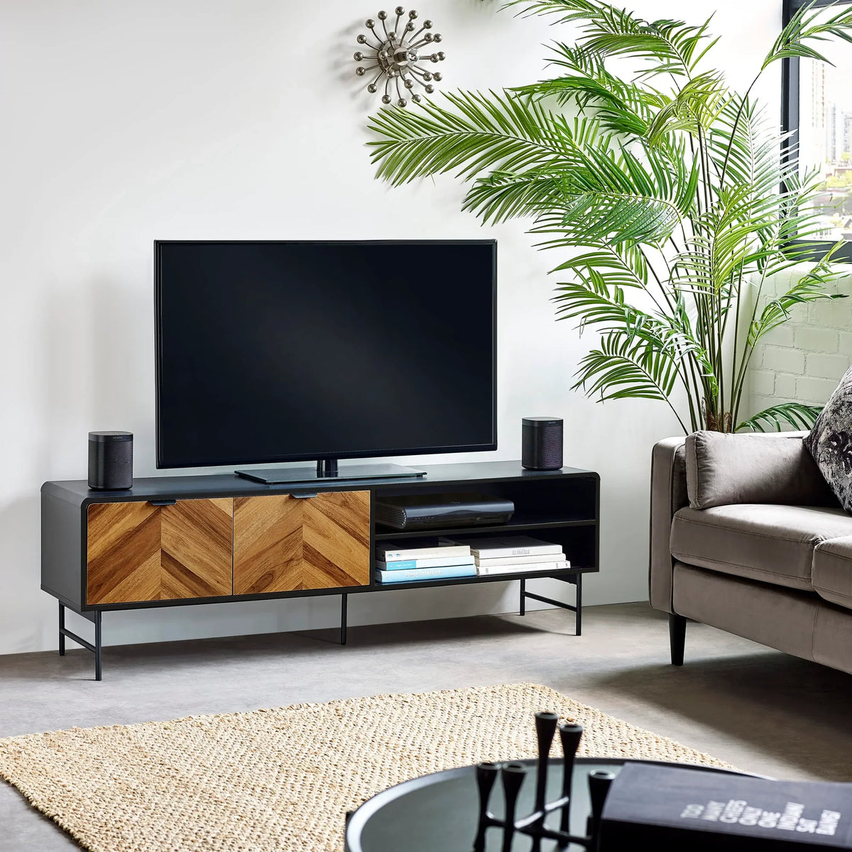 Modern TV stand with wood chevron doors, black frame, and open shelves in living room