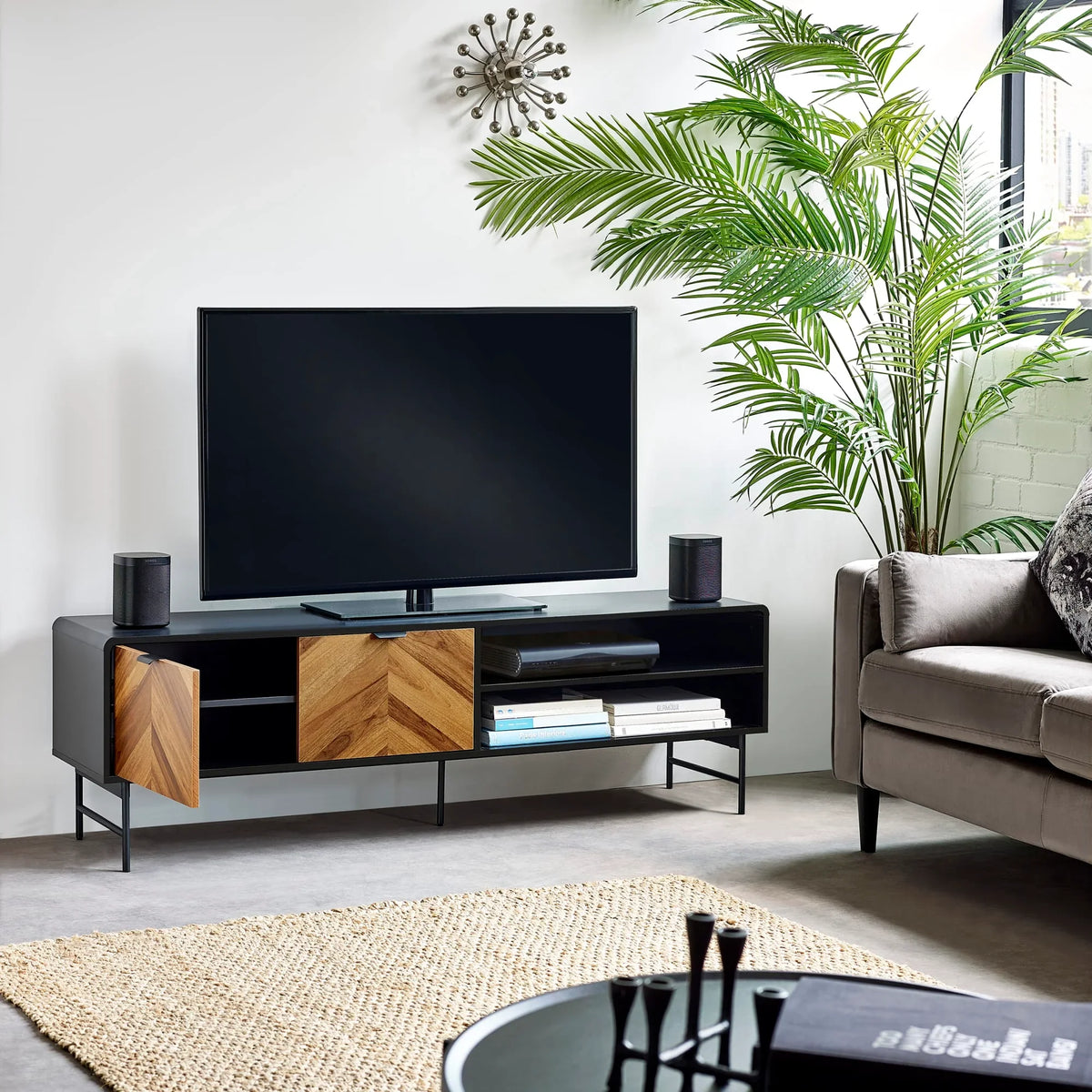 Modern TV unit with wood and black finish, open shelves, styled in living room with indoor plant