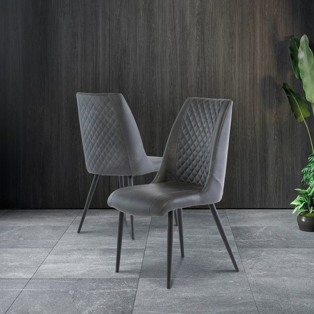 Grey velvet dining chairs with diamond stitching and angled legs on tiled floor