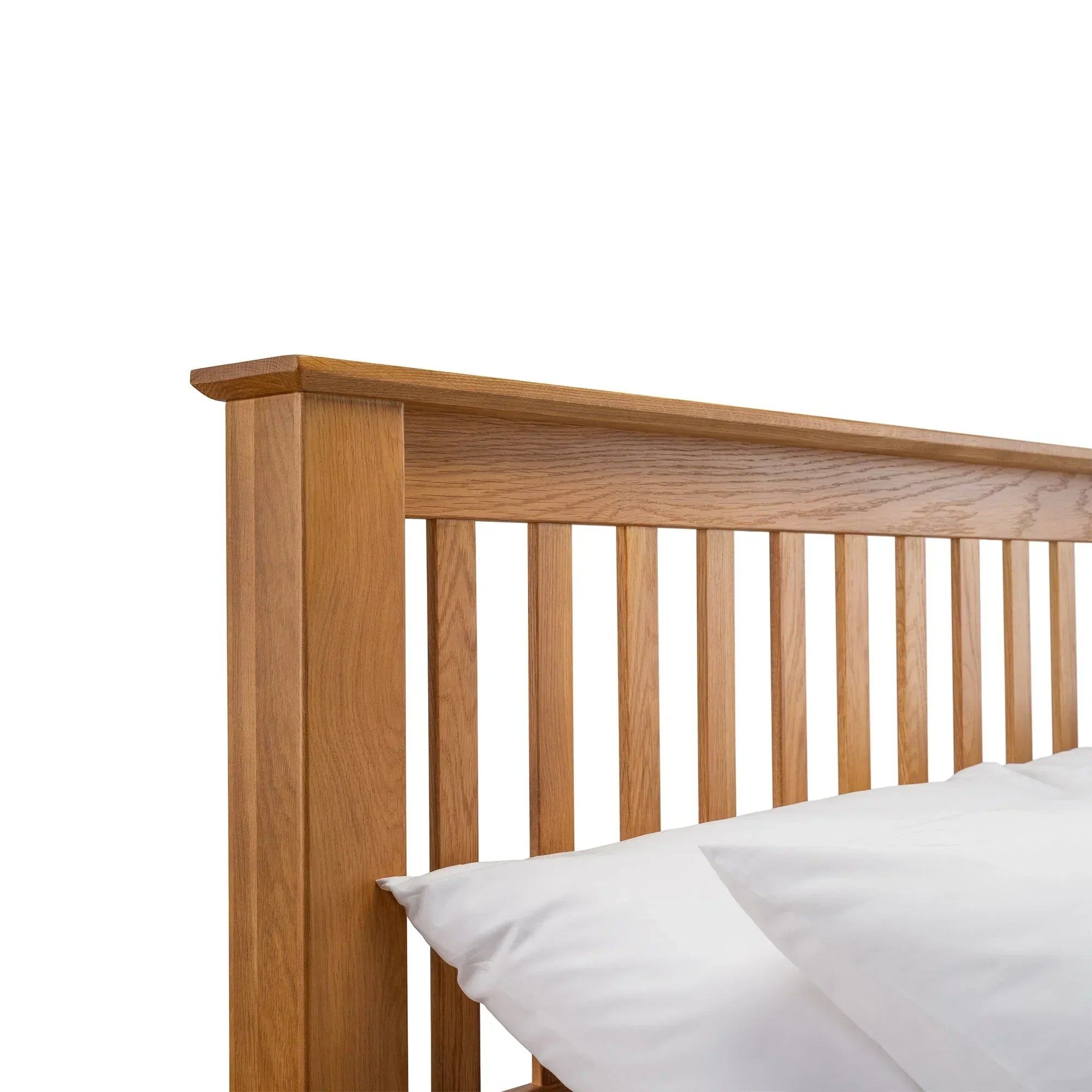 Solid oak bed frame with slatted headboard and white pillows, close-up detail