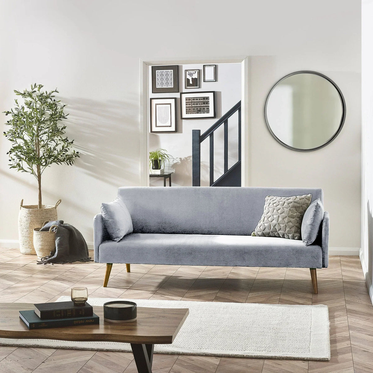 Grey sofa bed with angled wooden legs and cushions in a modern living room with decor accents
