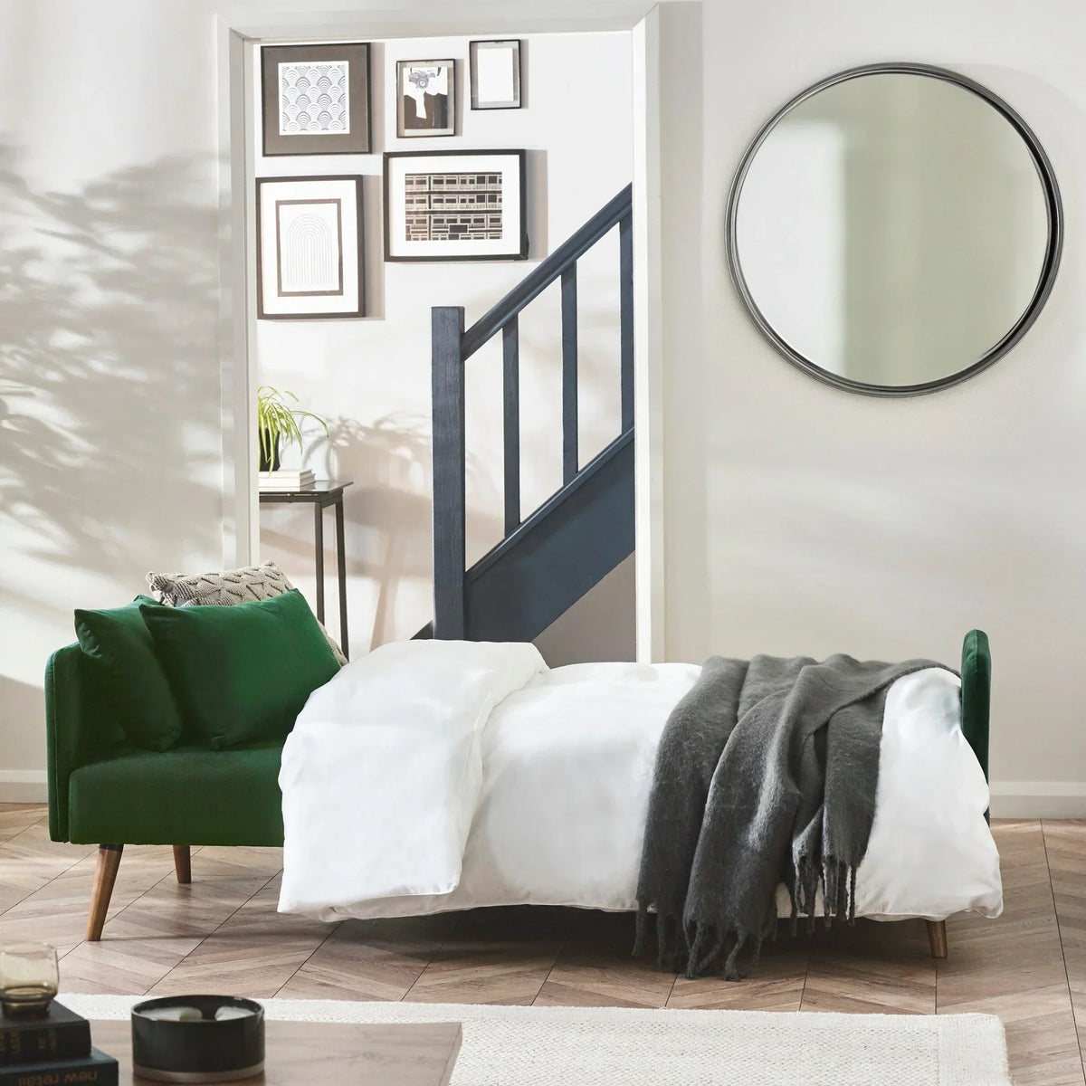 Green sofa bed extended as bed with white bedding and grey throw in modern living room