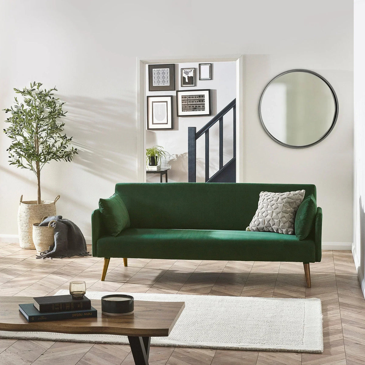 Green sofa bed with wooden legs and accent cushion in modern living room setting