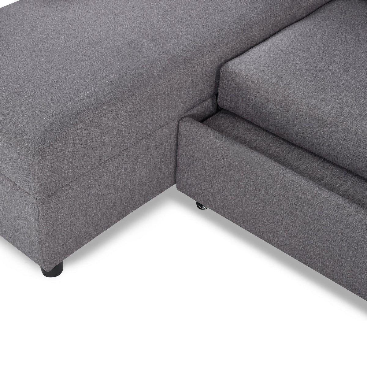 Grey sofabed with visible storage drawer and fabric upholstery, close-up corner view