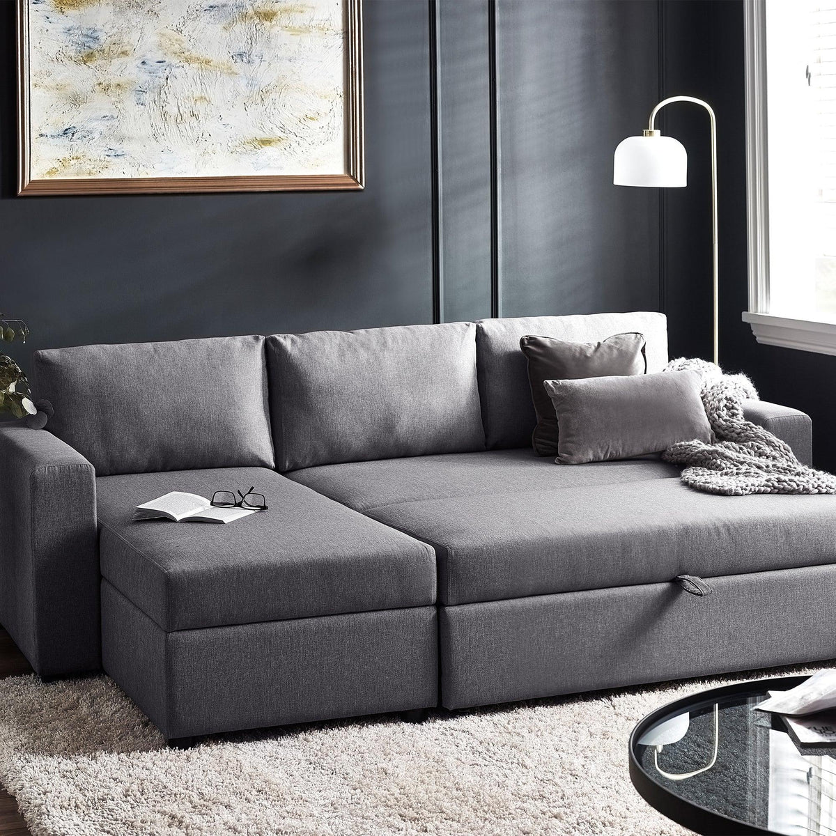 Grey fabric sofabed with storage, scatter cushions and throw in modern living room