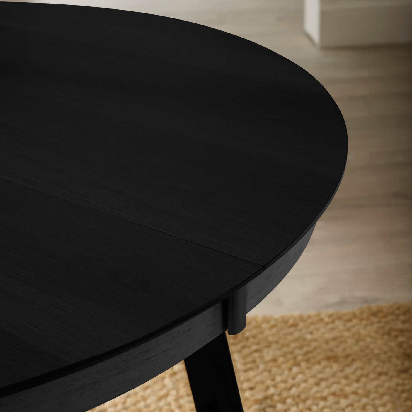 Close-up of black wooden dining table edge showing wood grain and extension join detail