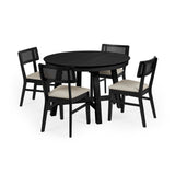 Set of four black wooden dining chairs with rattan backs and cream fabric seats around round black wooden table.