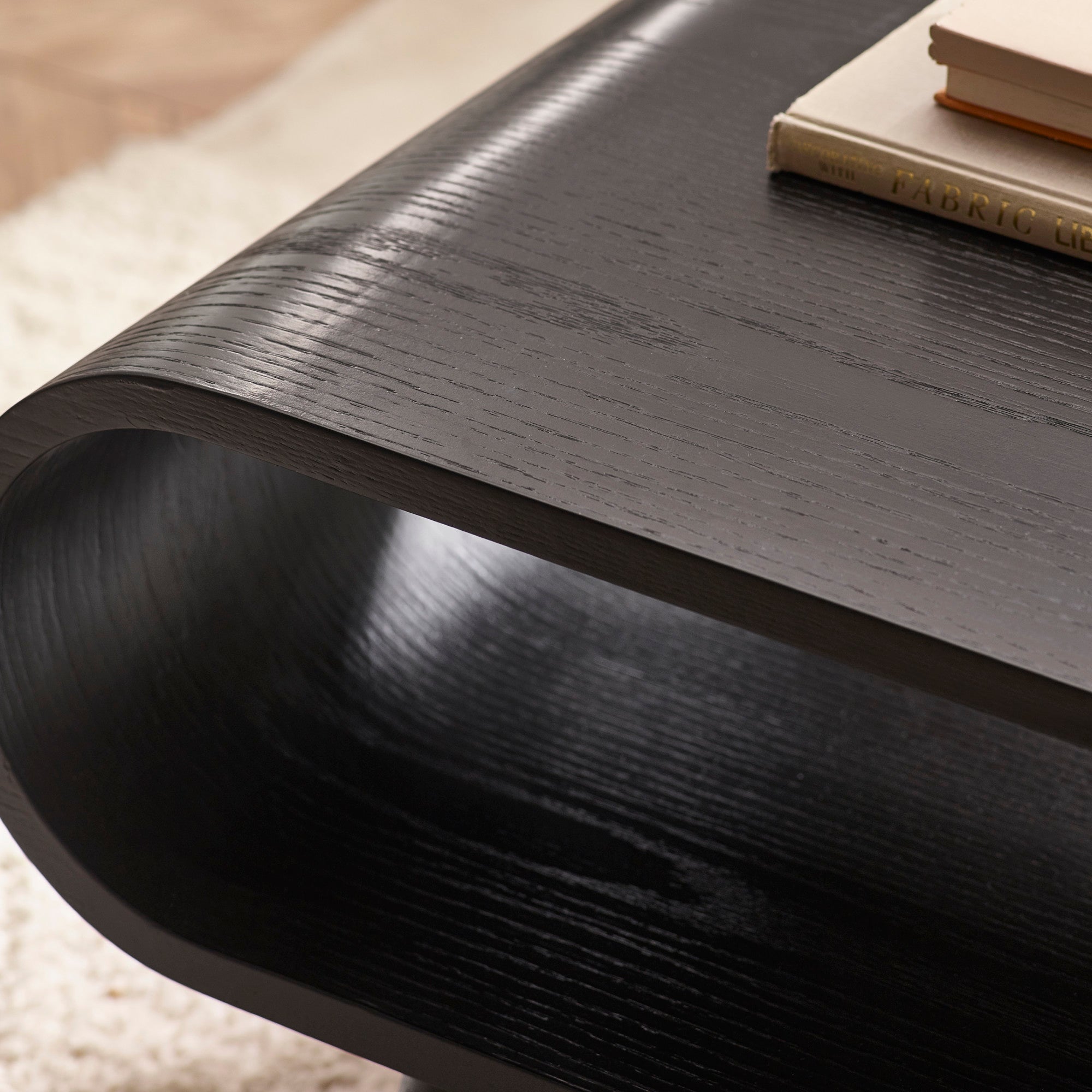 Close-up of black wood grain texture on coffee table with books stacked on open shelf