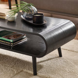 Close-up of coffee table surface with decorative tray, glass vase, and candle on black wood