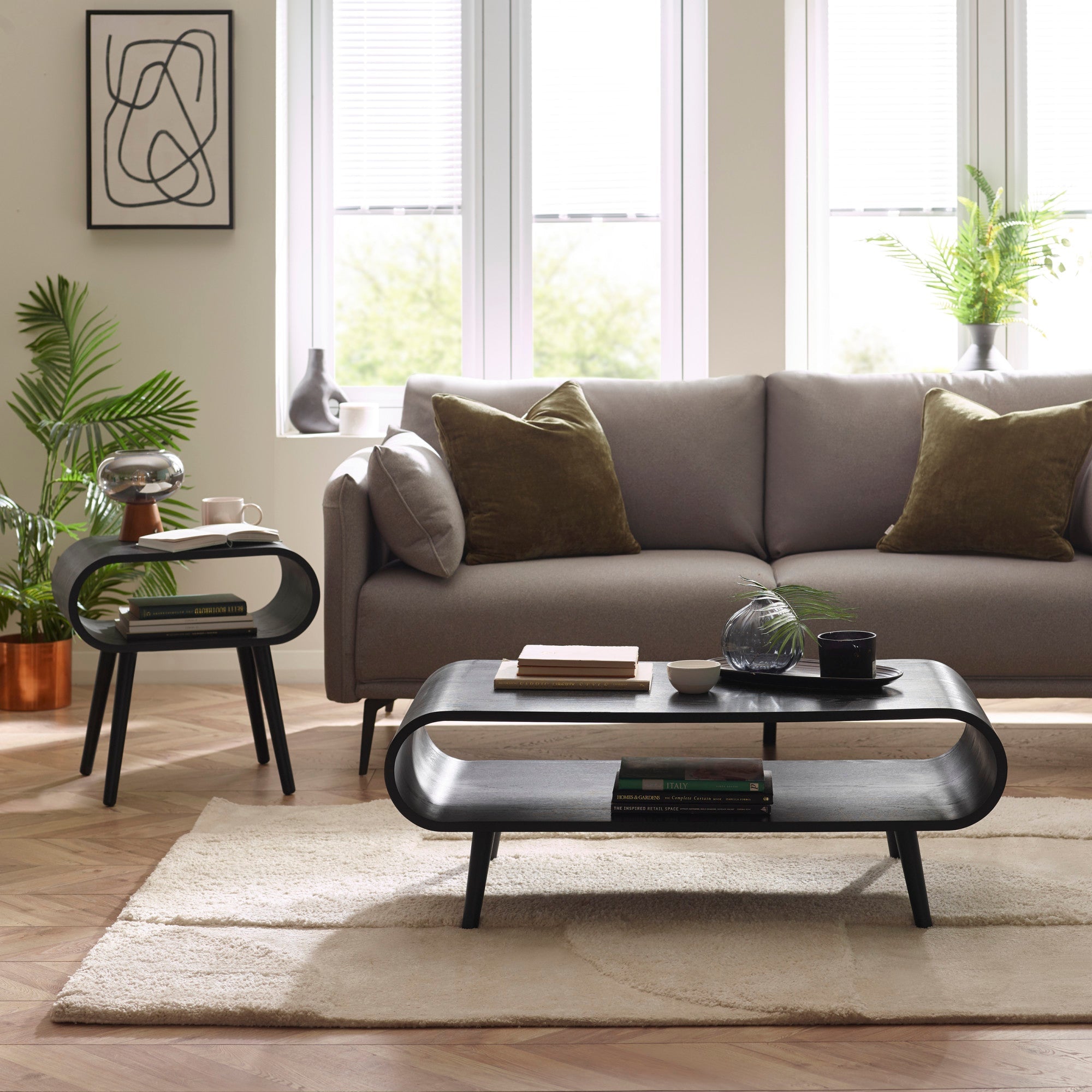 Black wood coffee table with rounded edges and tapered legs in a bright living room setting