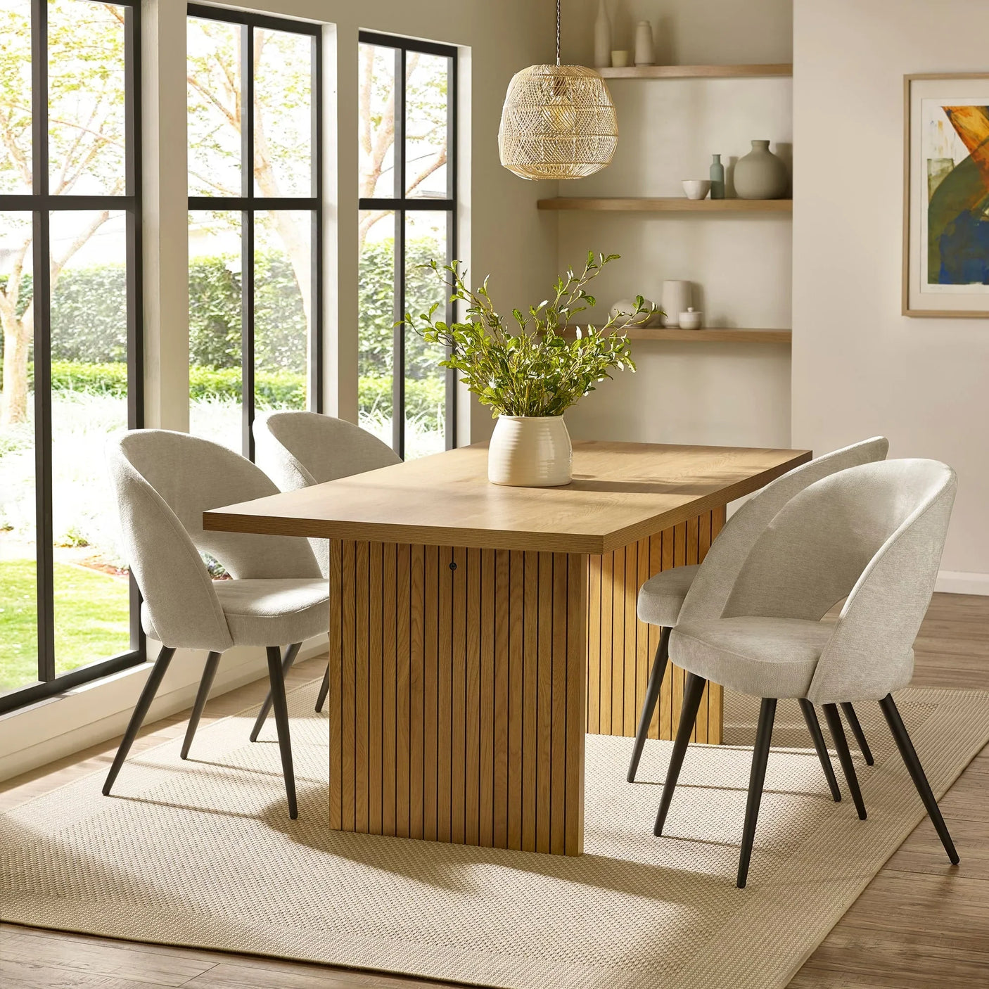 Modern oak dining table with light grey upholstered chairs in sunlit dining room