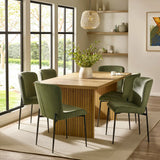 Oak dining table with green velvet chairs on beige rug in bright modern dining room