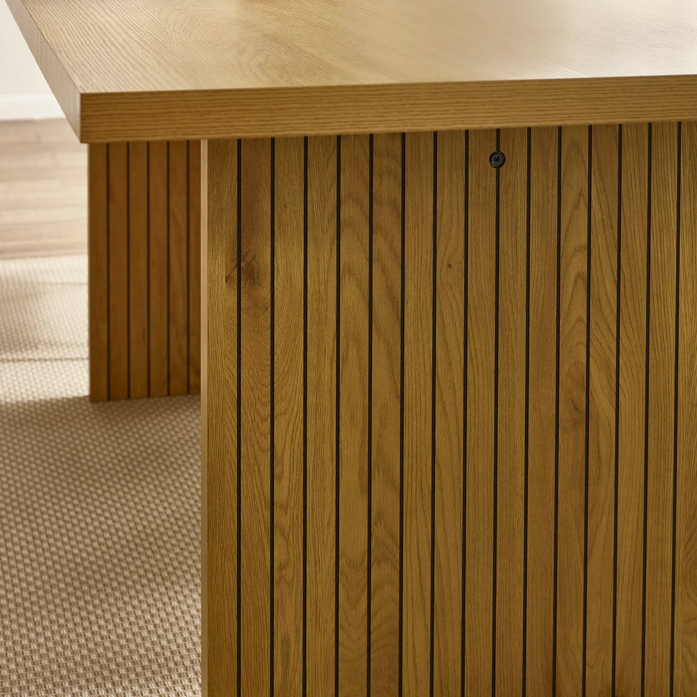 Oak dining table with slatted wooden base and rectangular top on textured beige rug
