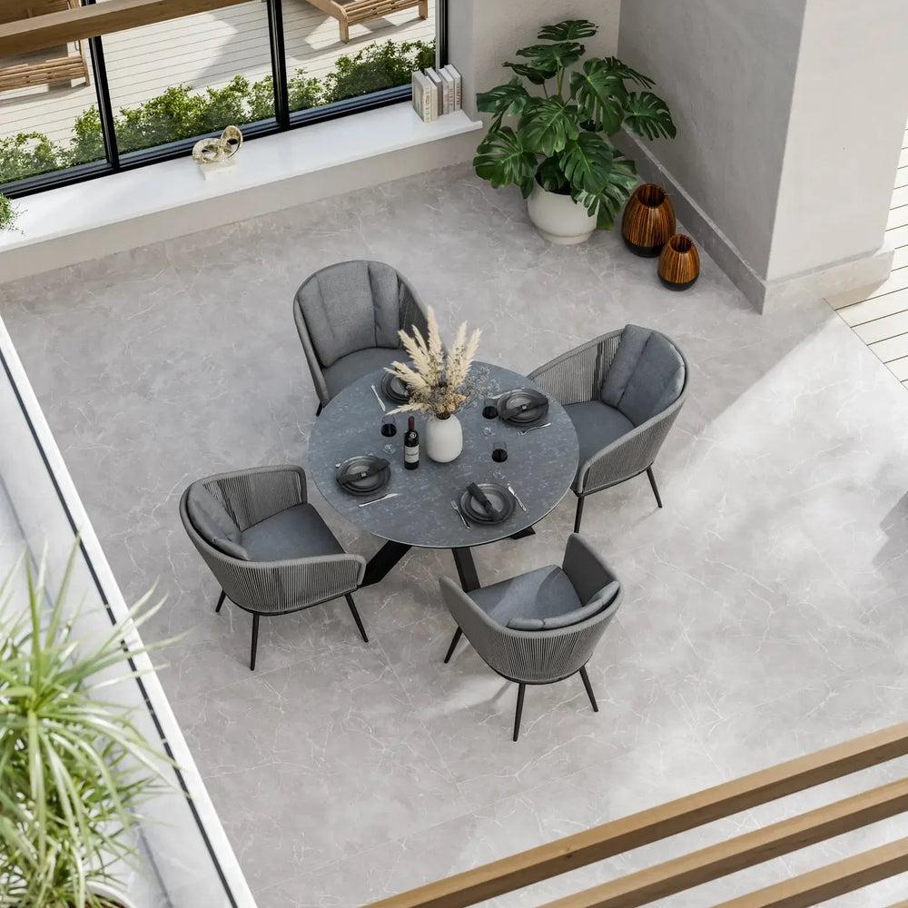 Modern grey dining set with four chairs and round table in bright indoor space