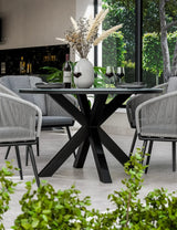 Modern black dining table with glass top, grey chairs, and decorative vase indoors