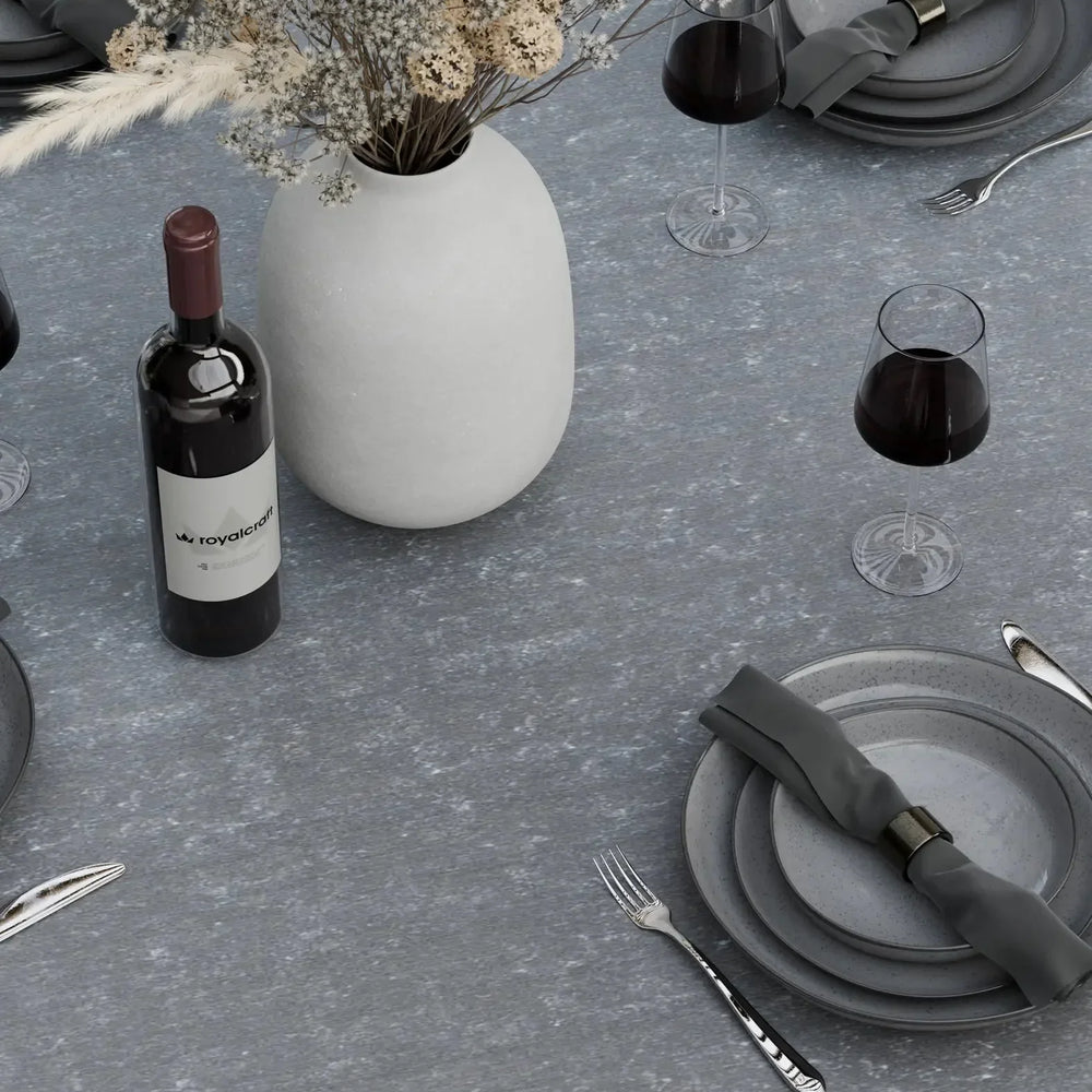 Round grey stone dining table set with plates, cutlery, wine glasses and white vase