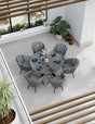 Round grey dining table set with six cushioned chairs in modern indoor setting