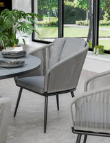 Grey rope dining chair with cushioned seat and backrest near round dining table
