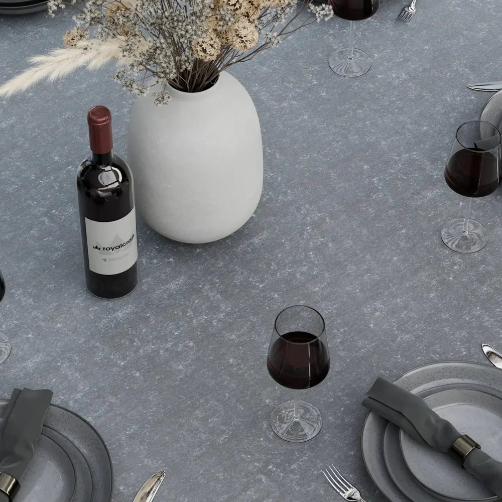 Grey stone dining table set with plates, cutlery, wine glasses, and ceramic vase centerpiece