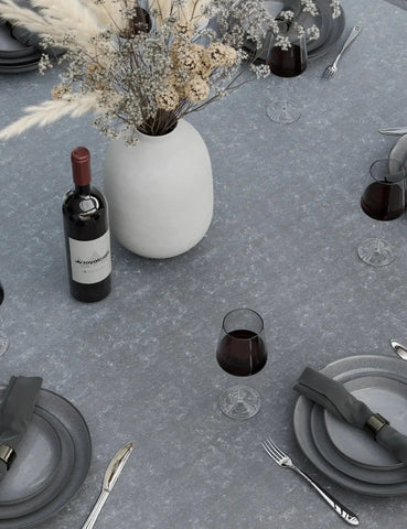 Grey stone dining table set with plates, cutlery, wine glasses, and ceramic vase centerpiece